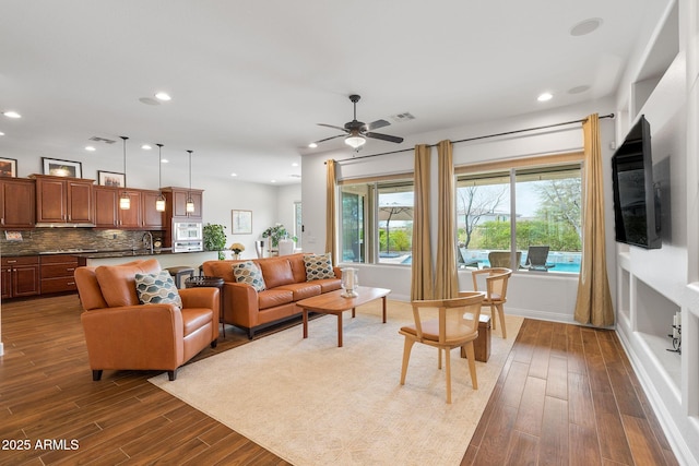 living room with baseboards, visible vents, dark wood-type flooring, and recessed lighting