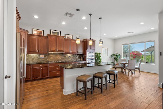 kitchen with dark wood-style flooring, a sink, visible vents, and decorative backsplash