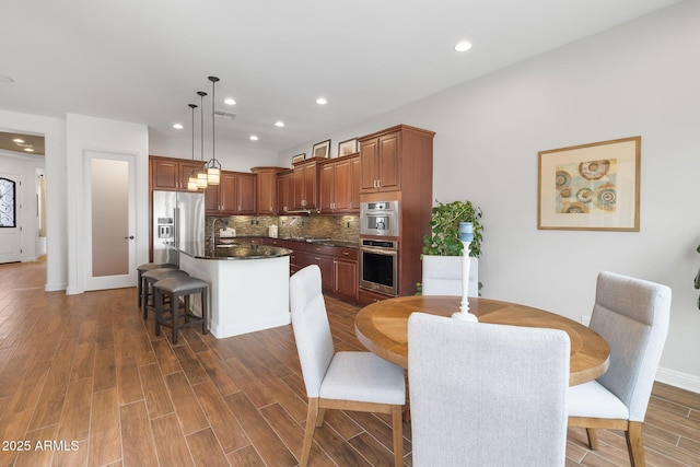 dining area with baseboards, wood finished floors, visible vents, and recessed lighting