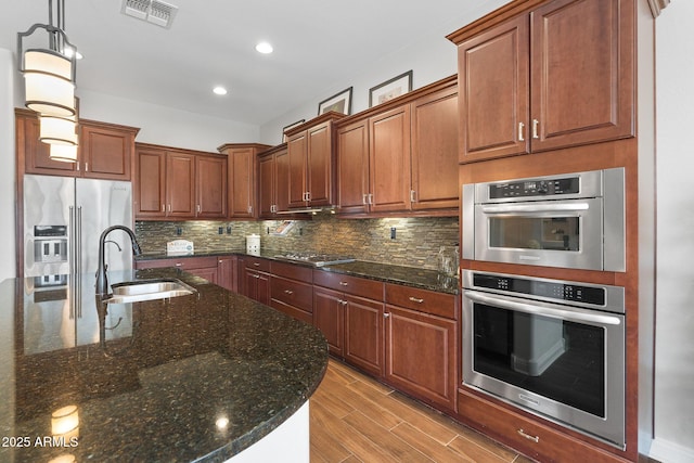 kitchen featuring high quality fridge, a sink, visible vents, decorative backsplash, and light wood finished floors