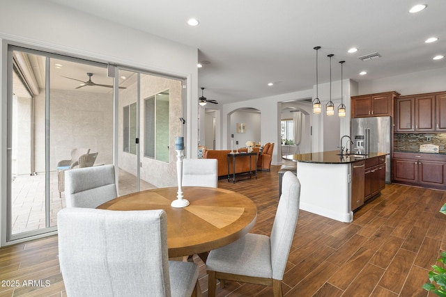 dining room with arched walkways, dark wood-style flooring, visible vents, and recessed lighting