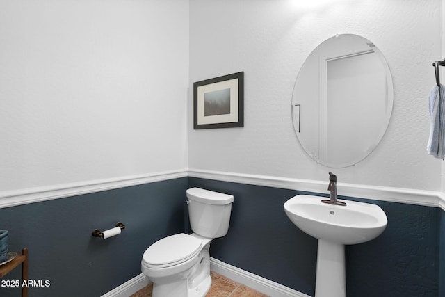 half bath featuring toilet, tile patterned flooring, and baseboards