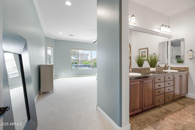 bathroom with double vanity, baseboards, crown molding, a sink, and recessed lighting