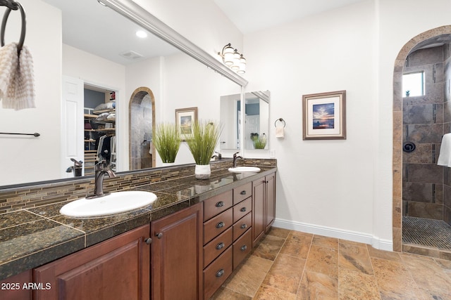 full bath featuring walk in shower, a sink, baseboards, and double vanity