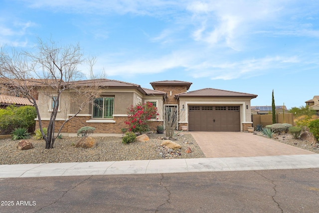 prairie-style house featuring a garage, concrete driveway, stucco siding, fence, and brick siding