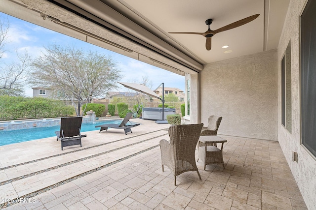 view of patio featuring a hot tub, an outdoor pool, and a ceiling fan