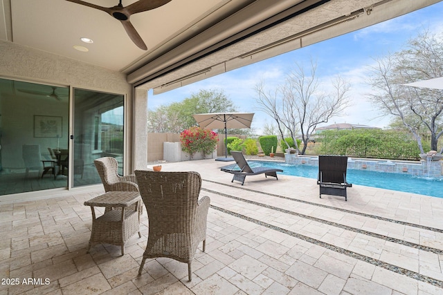 view of patio / terrace with a hot tub, fence, a ceiling fan, and a fenced in pool