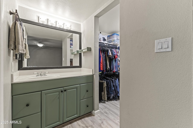 1927 E Hampton Ave Unit 204, Mesa, AZ 85204 - bathroom with vanity, wood finished floors, a textured wall, ceiling fan, and a walk in closet