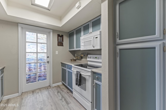 1927 E Hampton Ave Unit 204, Mesa, AZ 85204 - kitchen featuring white appliances, light wood-style flooring, light countertops, a tray ceiling, and glass insert cabinets