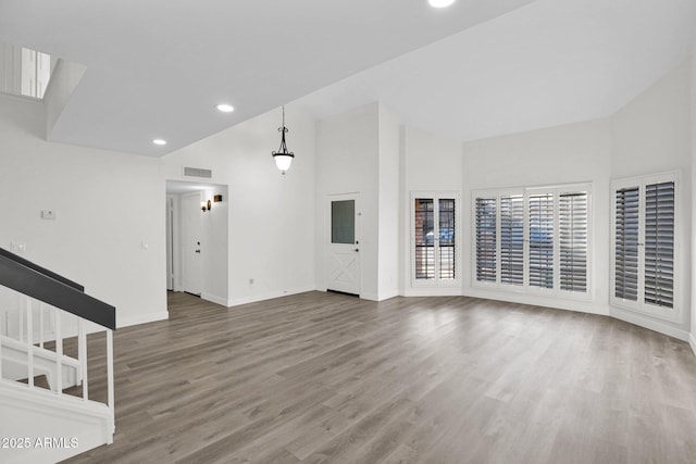 unfurnished living room with hardwood / wood-style floors and high vaulted ceiling