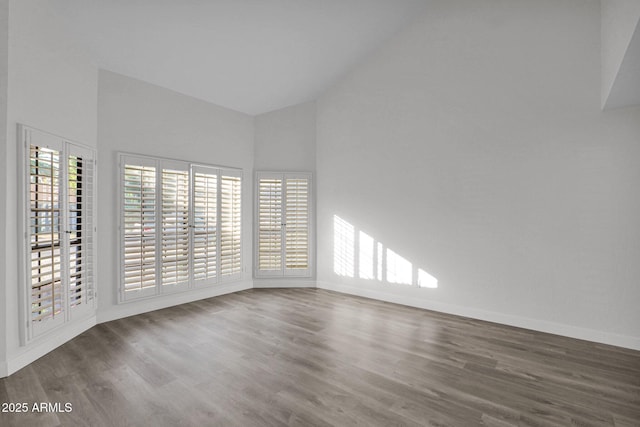 empty room featuring high vaulted ceiling and dark wood-type flooring