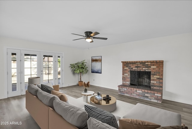 living room with a fireplace, ceiling fan, french doors, and wood-type flooring