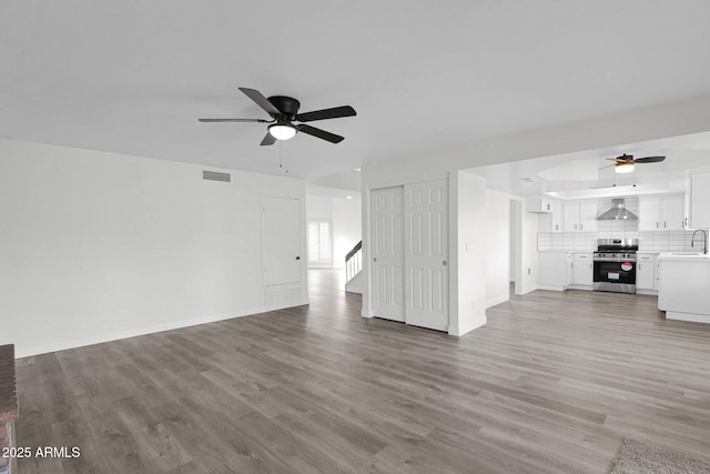 unfurnished living room featuring ceiling fan, sink, and light hardwood / wood-style flooring