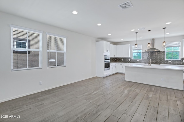 751 W Flintlock Way, Chandler, AZ 85286 - kitchen with wall chimney exhaust hood, light wood-style floors, tasteful backsplash, double oven, and white cabinetry