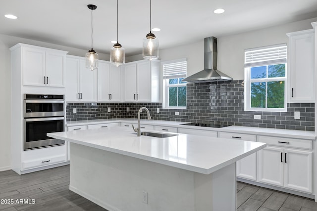 751 W Flintlock Way, Chandler, AZ 85286 - kitchen with wall chimney exhaust hood, a sink, stainless steel double oven, black electric stovetop, and light wood-type flooring