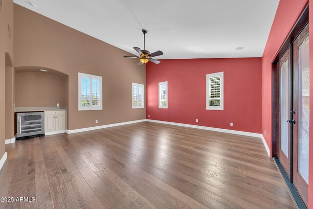 1435 E Rancho Dr, Phoenix, AZ 85014 - unfurnished living room featuring baseboards, wine cooler, vaulted ceiling, and hardwood / wood-style flooring
