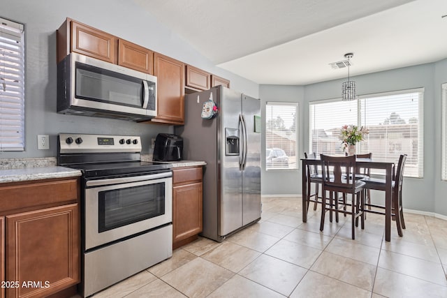 kitchen with lofted ceiling, visible vents, light countertops, appliances with stainless steel finishes, and brown cabinetry