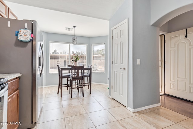 dining area featuring arched walkways, visible vents, baseboards, and light tile patterned floors