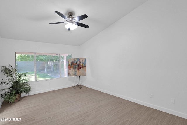 spare room with ceiling fan, vaulted ceiling, and light wood-type flooring