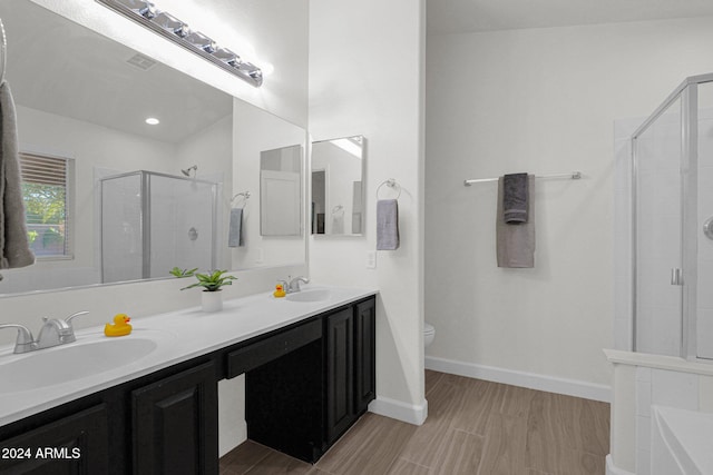 bathroom featuring hardwood / wood-style flooring, vanity, toilet, and a shower with door