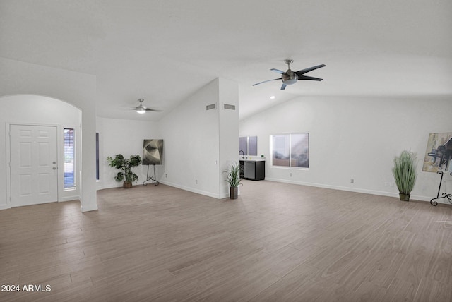 unfurnished living room with lofted ceiling, ceiling fan, and light wood-type flooring