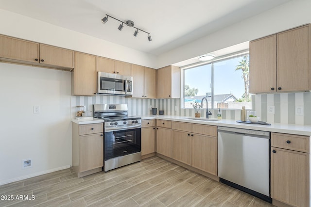 kitchen with stainless steel appliances, a sink, backsplash, light countertops, and light brown cabinetry