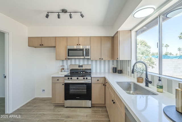 kitchen with appliances with stainless steel finishes, a sink, light countertops, and light brown cabinets