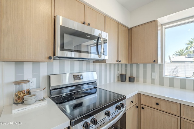 kitchen featuring stainless steel appliances, backsplash, light countertops, and light brown cabinets