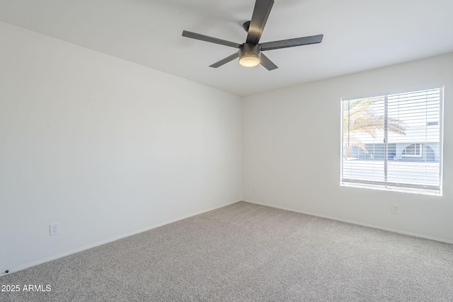 carpeted spare room with a ceiling fan and baseboards