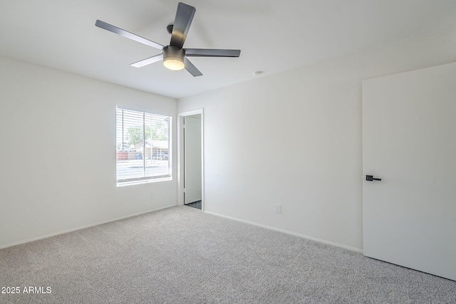 carpeted spare room featuring ceiling fan and baseboards