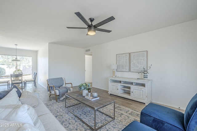 living room featuring a ceiling fan, baseboards, and wood finished floors
