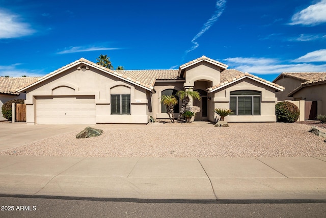 mediterranean / spanish home with a garage, a tiled roof, and stucco siding