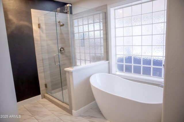 full bath with a freestanding bath, marble finish floor, a shower stall, and a healthy amount of sunlight