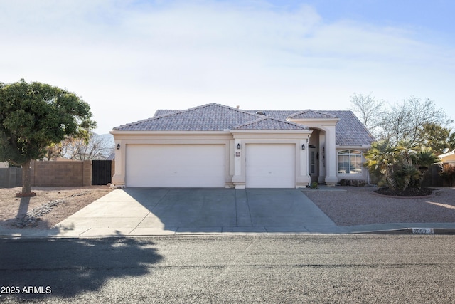 view of front of home featuring a tile roof, stucco siding, concrete driveway, an attached garage, and fence