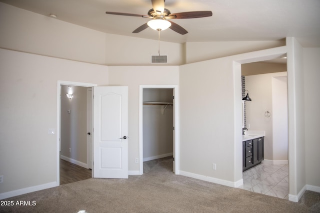 unfurnished bedroom featuring lofted ceiling, a sink, visible vents, and light colored carpet