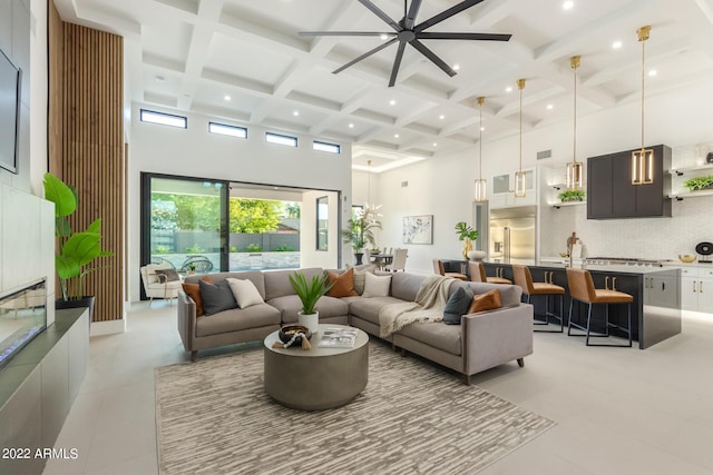 living room featuring beamed ceiling, a towering ceiling, ceiling fan, and coffered ceiling