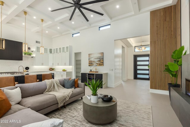 living room with beam ceiling, ceiling fan, a healthy amount of sunlight, and a high ceiling