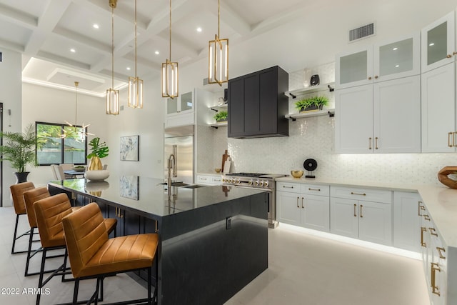 kitchen featuring backsplash, coffered ceiling, high end appliances, a kitchen island with sink, and white cabinetry