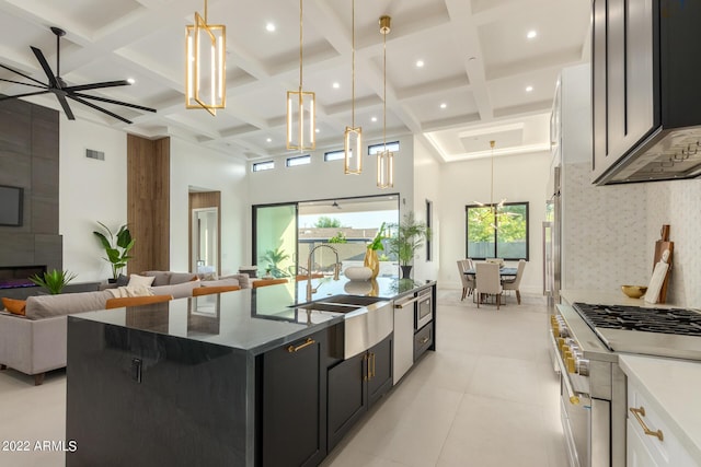 kitchen with hanging light fixtures, white cabinets, stainless steel appliances, and a center island with sink