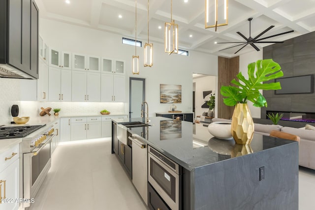 kitchen featuring coffered ceiling, built in microwave, a kitchen island with sink, dark stone countertops, and white cabinets