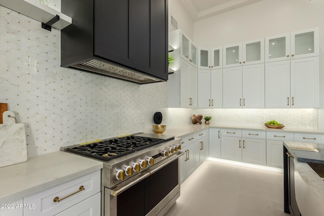 kitchen featuring decorative backsplash, light stone countertops, white cabinetry, and high end stainless steel range