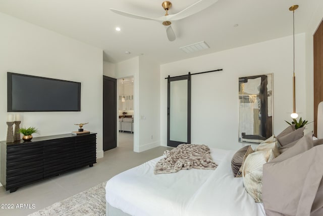 bedroom featuring connected bathroom, a barn door, and ceiling fan