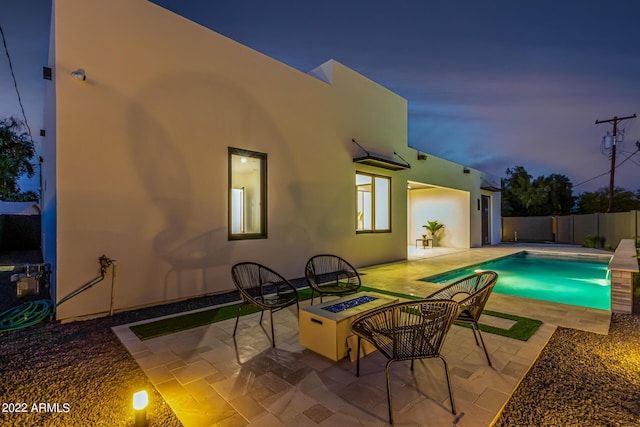 pool at dusk with a fire pit and a patio area