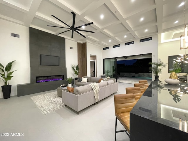 living room with a fireplace, a high ceiling, coffered ceiling, and beam ceiling