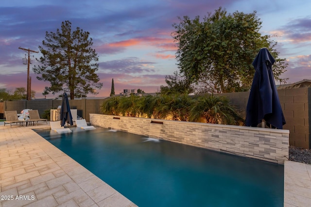 pool at dusk with a patio area