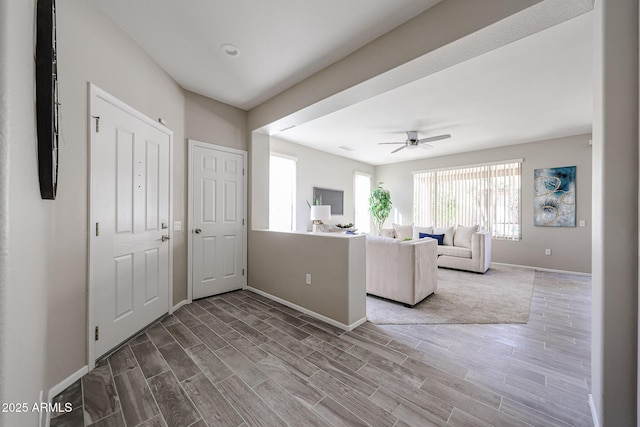 unfurnished living room featuring ceiling fan, baseboards, and wood finish floors