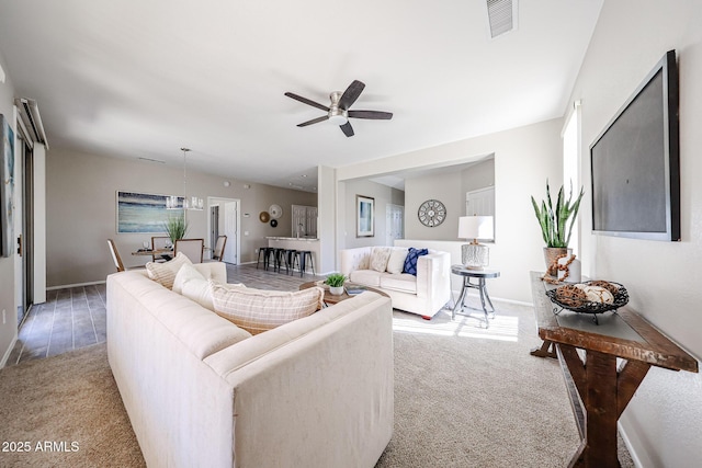 living room featuring baseboards, carpet flooring, visible vents, and a ceiling fan