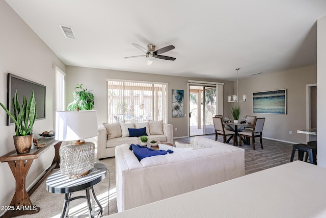 living area with baseboards, visible vents, a ceiling fan, and wood finished floors