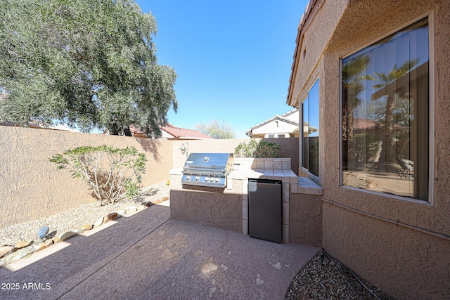 view of patio with an outdoor kitchen, a fenced backyard, and grilling area