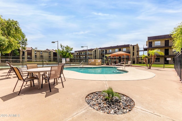 pool with a patio, fence, and a residential view